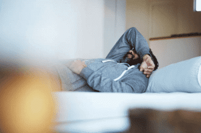 Mand ligger med hovedpine i sengen