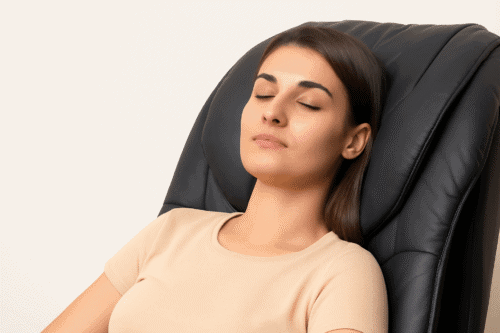 Kvinde sidder roligt i en massagestol med lukkede øjne for at illustrere afslapning og mindre angst.